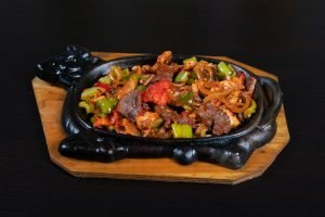 Sauté de bœuf appétissant avec des légumes colorés servi sur une assiette chaude grésillante.