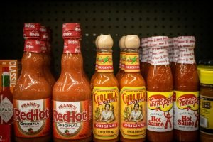 L'étagère présente diverses bouteilles de sauce piquante.